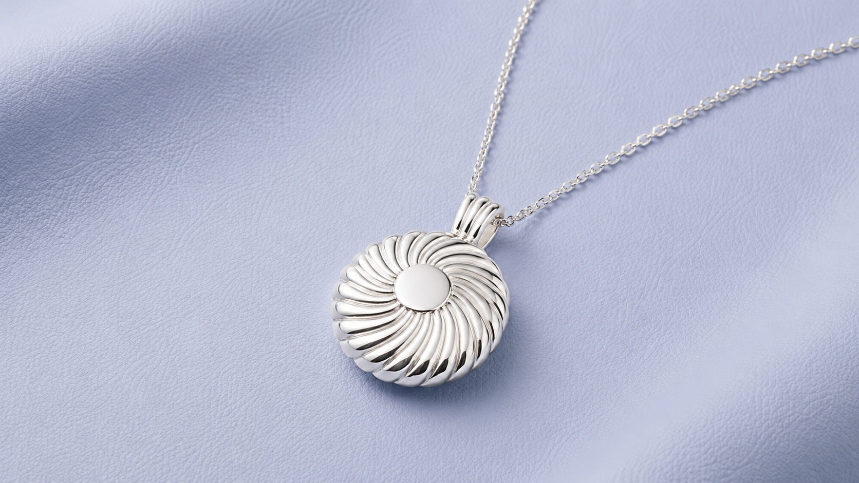 Polished silver pendant on soft blue surface